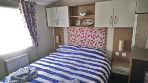 Un dormitorio con una cama con rayas azules y blancas. en Bude Caravan Caromax - Families and Couples Only, en Bude 23 fotos más