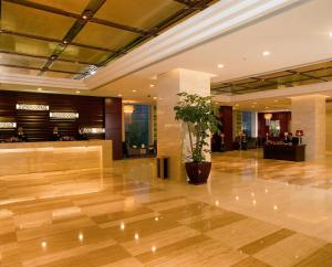 a lobby with a potted plant in the middle at Beijing Tibet Hotel in Beijing