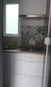 uma cozinha com armários brancos, um lavatório e uma janela em Taos Single - Camping Du Nord em Dirbach