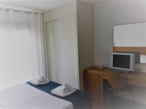 a bedroom with a desk with a computer and a monitor at Lacroma Bio Hotel & Apartments in Grado