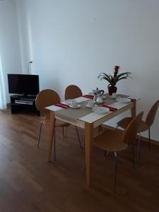 mesa de comedor con sillas y TV en Lacroma Bio Hotel & Apartments, en Grado