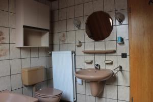 ein Badezimmer mit Waschbecken, Toilette und Spiegel in der Unterkunft Ferienwohnungen im Gästehaus Sieberns in Carolinensiel + 17 Fotos