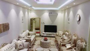 ein Wohnzimmer mit Sofas und einem Flachbild-TV in der Unterkunft زائر الشمال للشقق الفندقية in Sakaka