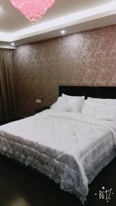1 dormitorio con 1 cama blanca grande y pared en زائر الشمال للشقق الفندقية en Sakaka