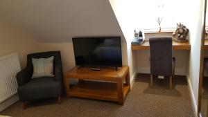 uma sala de estar com uma televisão e duas cadeiras e uma mesa em The Barn Courtyard em Shepshed