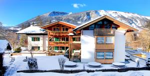 ein Haus im Schnee mit einem Berg im Hintergrund in der Unterkunft Naturhotel Schütterbad in Unken