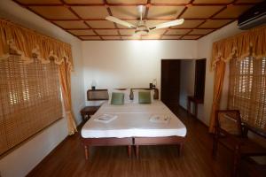 a bedroom with a bed with white sheets and green pillows at Rajadhani 5th Season in Varkala +34 photos