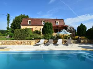 a house with a swimming pool with chairs and an umbrella at Cosy holiday home with swimming pool in Mouzens