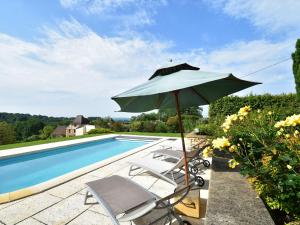 ein Sonnenschirm und Stühle neben einem Pool in der Unterkunft Cosy holiday home with swimming pool in Mouzens