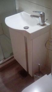 La salle de bains est pourvue d'un lavabo blanc et d'une douche. dans l'établissement Ferienwohnung Ananda auf Fehmarn, à Fehmarn