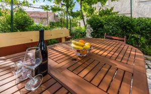 a bottle of wine and a bowl of fruit on a wooden table at Three-Bedroom Apartment Meden in Pomer