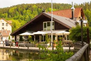 un edificio con mesas y sombrillas junto a un río en Self-check-in Ferienwohnungen & Apartments am Bergsee en Triberg