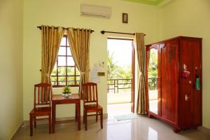 a dining room with a table and chairs and a window at Cat Tien Guesthouse in Mui Ne