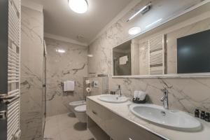 a bathroom with two sinks and a toilet at Boutique Hotel Acacia in Lovran
