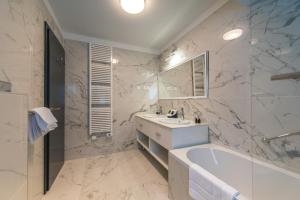 a white bathroom with a tub and a sink at Boutique Hotel Acacia in Lovran