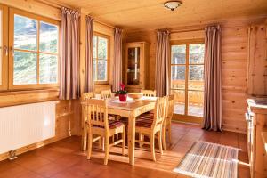 a dining room with a table and chairs and windows at Bauerndörfl Hüttschlag in Hüttschlag