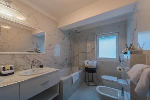 a bathroom with a sink and a toilet and a tub at Boutique Hotel Acacia in Lovran
