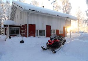 a snowmobile parked in the snow in front of a building at Riverhouse Lumo in Ivalo