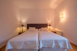 een slaapkamer met een groot bed met witte lakens bij Hotel El Molino de Salinas in Salinas de Pisuerga