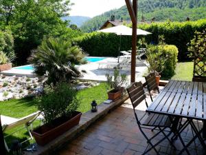 un patio con mesa, sillas y piscina en Casa Webb, en Bagni di Lucca