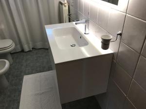 y baño con lavabo blanco y aseo. en La Poderina Appartamenti, en Castelnuovo dellʼAbate