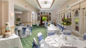 um salão de banquetes com mesas brancas e cadeiras azuis em The Birch Hotel em Haywards Heath