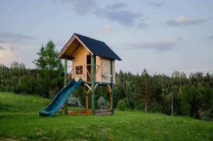 a play house with a slide in a field at Podhalańskie Domki u Magdusi i Marcina z Jacuzzi in Maniowy