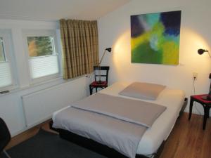 a bedroom with a bed with two chairs and a painting at Hotel Schlafschön in Hannoversch Münden