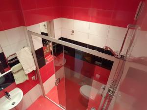 La salle de bains rouge et blanche est pourvue de toilettes et d'une douche. dans l'établissement Apartamentai Palangos centre, à Palanga