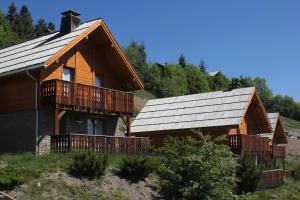 a log cabin with a porch and a roof at Chalets de Praroustan by Actisource in Pra-Loup