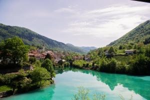 a river in a valley with a town in the background at Penzion Šterk in Most na Soči