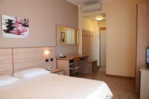 ミラノ・マリッティマにあるHotel Mirageのベッドとデスクが備わるホテルルームです。