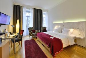 Habitación de hotel con cama grande y escritorio. en Best Western Premier Hotel Victoria, en Freiburg im Breisgau
