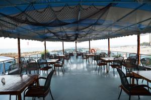 un restaurante vacío con mesas y sillas y la playa en Hotel Hercules Jupiter en Jupiter