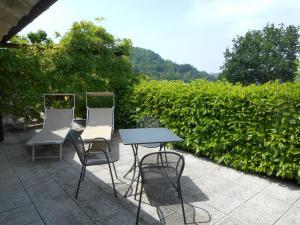 three chairs and a table in front of a hedge at Agriturismo Cascina Serra in Cossano Belbo