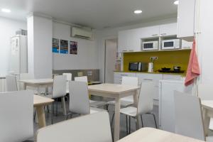 a kitchen with white tables and white chairs at Alberguinn in Barcelona