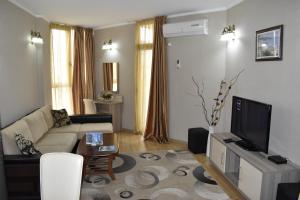 a living room with a couch and a tv at Hotel Orbi Plaza in Batumi
