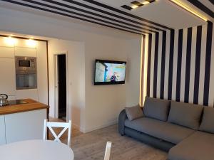 a living room with a couch and a tv on a wall at Apartament 200m do plaży in Gdańsk