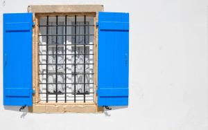 a blue window with bars on a white wall at Margarita Hotel in Kythira