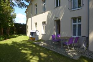 a table and purple chairs in front of a house at Apartamenty Rybak 3 in Niechorze