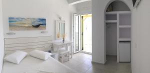 a white bedroom with a bed and a window at Aegeo Inn in Antiparos