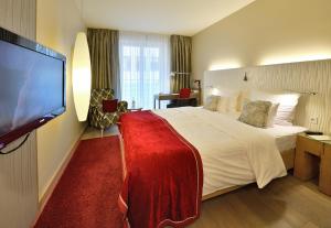 um quarto de hotel com uma cama grande e uma televisão de ecrã plano em Best Western Premier Hotel Victoria em Friburgo em Brisgóvia