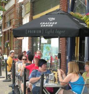 eine Gruppe von Menschen, die an einem Tisch unter einem Schirm sitzen in der Unterkunft Canalside Restaurant, Inn & Kitchen Store in Port Colborne