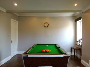 a pool table in a room with a clock on the wall at Higherlands in Kingsley