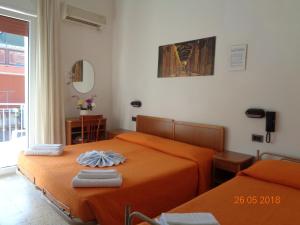 2 bedden in een slaapkamer met oranje lakens bij Hotel Lariana in Rimini