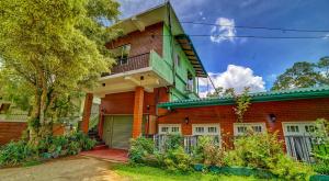 una casa de ladrillo rojo con techo verde en Hanthana Holiday Rooms, en Kandy