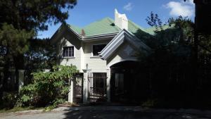 a white house with a green roof and a gate at Koinonia Retreat CenteR in Baguio