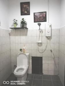 a bathroom with a toilet and a tv on the wall at Alsafffa Homestay in Pantai Cenang