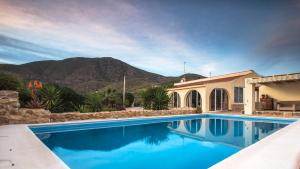 a swimming pool in front of a house with a mountain at Casa de la Piña in Hondón de los Frailes