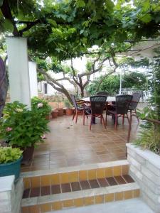 un patio con mesa y sillas bajo un árbol en Apartmani Miletić, en Jelsa